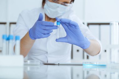 Koruyucu gözlüklü profesyonel kadın bilim adamının laboratuarda reaktörlerle deney yapması. Tıp ve araştırma konsepti