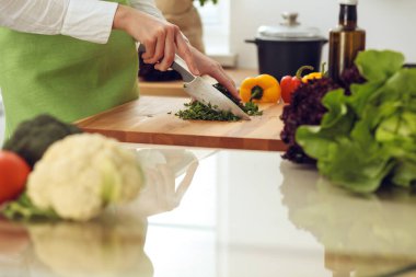 Mutfakta pişen bilinmeyen insan elleri. Kadın sebze salatasıyla meşgul. Sağlıklı yemek ve vejetaryen gıda konsepti.