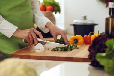 Mutfakta pişen bilinmeyen insan elleri. Kadın sebze salatasıyla meşgul. Sağlıklı yemek ve vejetaryen gıda konsepti.