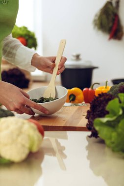 Mutfakta pişen bilinmeyen insan elleri. Kadın sebze salatasıyla meşgul. Sağlıklı yemek ve vejetaryen gıda konsepti.