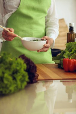 Mutfakta pişen bilinmeyen insan elleri. Kadın sebze salatasıyla meşgul. Sağlıklı yemek ve vejetaryen gıda konsepti.