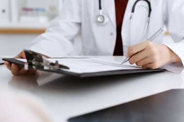 Bilinmeyen kadın-doktor hastaya danışmanlık yaparken başvuru formu dolduruyor. Tıp konsepti