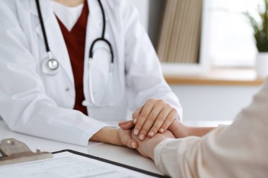 Kadın hastasına güvence veren kimliği belirsiz kadın doktorun elleri, yakın plan. Tıp konsepti
