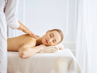 Güzel bir kadın kapalı gözlerle sırt masajından hoşlanıyor. Spa tedavisi kavramı
