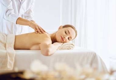 Güzel bir kadın kapalı gözlerle sırt masajından hoşlanıyor. Spa tedavisi kavramı