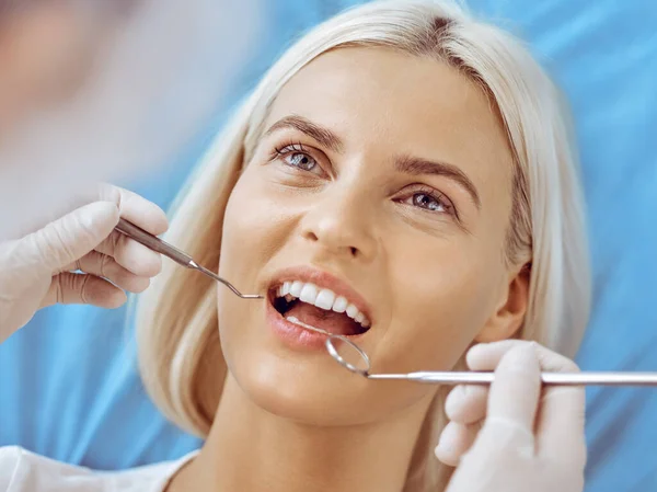 Diş hekiminde dişçi tarafından muayene edilen gülümseyen sarışın kadın. Sağlıklı diş ve ilaç konsepti — Stok fotoğraf