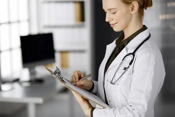 Весёлая улыбающаяся женщина-врач использует планшет в клинике. Портрет доброжелательной женщины-врача за работой. Перфектное медицинское обслуживание в больнице. Концепция медицины — стоковое фото