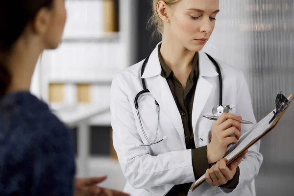 Joyeux sourire femme médecin et patiente discutant de l'examen de santé en cours tout en étant assis à la clinique. Service médical parfait à l'hôpital. Concept de médecine — Photo