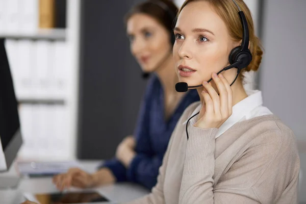 Femme d'affaires parlant par casque pendant qu'elle était assise au bureau. Centre d'appels et divers groupes de personnes en affaires — Photo