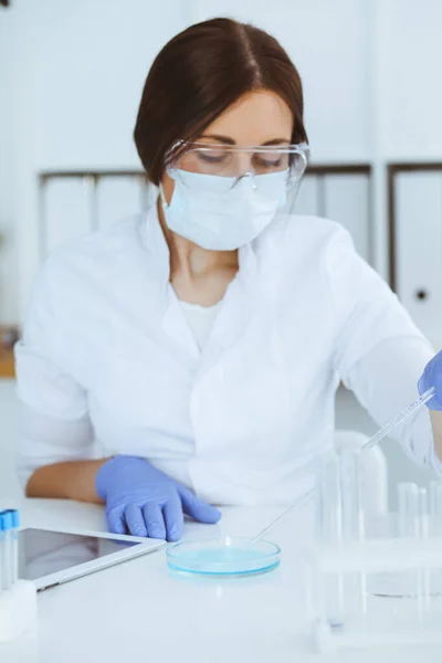 Close-up de cientista profissional feminino em óculos de proteção fazendo experiência com reagentes em laboratório. Medicina e conceito de pesquisa — Fotografia de Stock