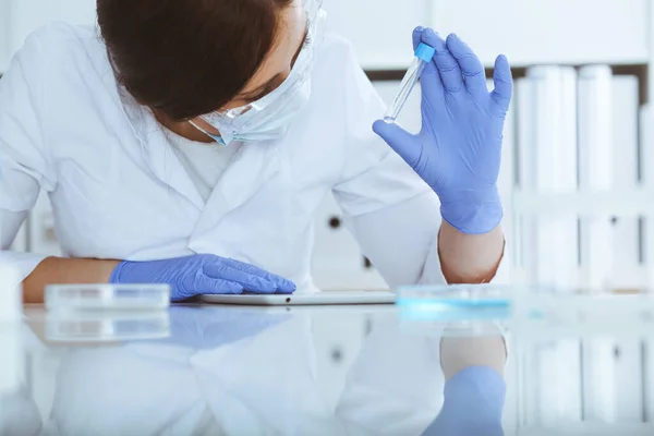 Close-up de cientista profissional feminino em óculos de proteção fazendo experiência com reagentes em laboratório. Medicina e conceito de pesquisa — Fotografia de Stock