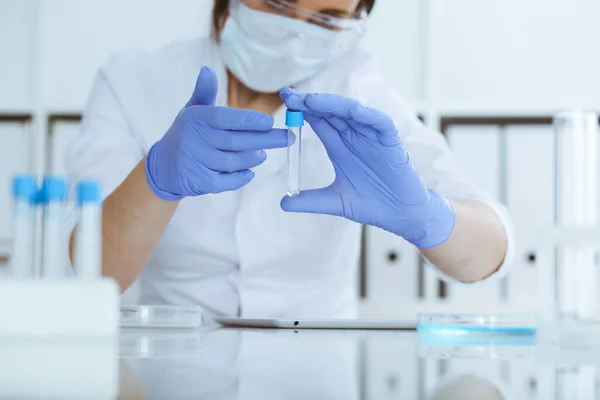 Close-up de cientista profissional feminino em óculos de proteção fazendo experiência com reagentes em laboratório. Medicina e conceito de pesquisa — Fotografia de Stock