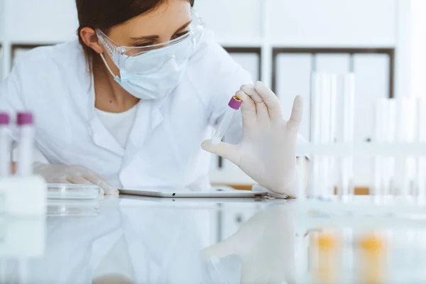 Profi női tudós közelkép védőszemüvegben kísérletezik reagensekkel a laboratóriumban. Orvosi és kutatási koncepció — Stock Fotó