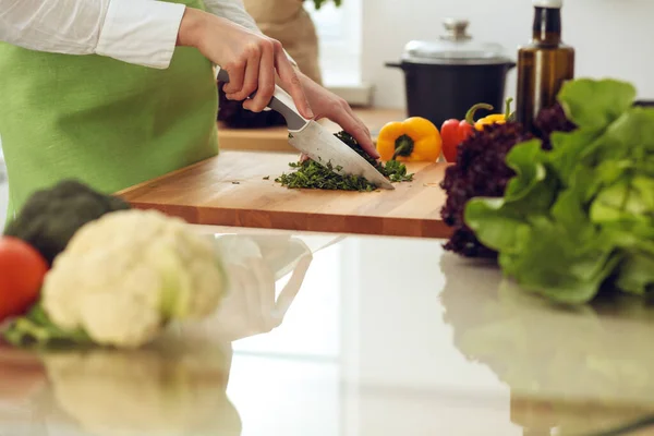 Mutfakta pişen bilinmeyen insan elleri. Kadın sebze salatasıyla meşgul. Sağlıklı yemek ve vejetaryen gıda konsepti.