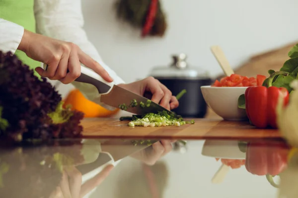 Manos humanas desconocidas cocinando en la cocina. Mujer cortando cebolla verde. Comida saludable y concepto de comida vegetariana —  Fotos de Stock