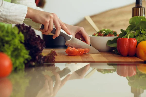 Manos humanas desconocidas cocinando en la cocina. Mujer cortando tomates rojos. Comida saludable y concepto de comida vegetariana —  Fotos de Stock