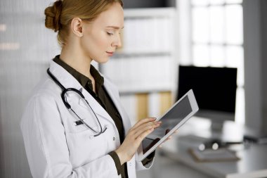 Klinikte tablet bilgisayar kullanan güler yüzlü bir bayan doktor. Hastanede mükemmel bir tıbbi hizmet. Tıp konsepti