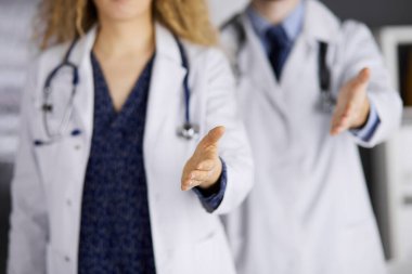 İki doktor ayakta durup el sıkışmak ya da hayat kurtarmak için yardım eli uzatıyorlar. Tıbbi yardım, viral enfeksiyon ve tıp konseptiyle mücadele