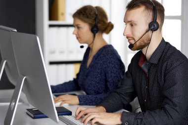 Modern ofiste otururken kulaklıkla konuşan kızıl sakallı bir iş adamı. Çağrı merkezinde çeşitli insanlar var. Tele pazarlama ve müşteri hizmetleri