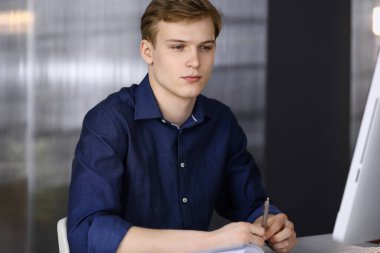 Bilgisayarla çalışan genç sarışın iş adamı. Girişim işi, başarı için çok çalışmak ve zamanın dışında çalışmak demektir.