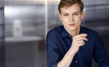 Genç sarışın işadamı iş yerinde bilgisayarla strateji düşünüyor. Girişim işi, başarı için çok çalışmak ve zamanın dışında çalışmak demektir.