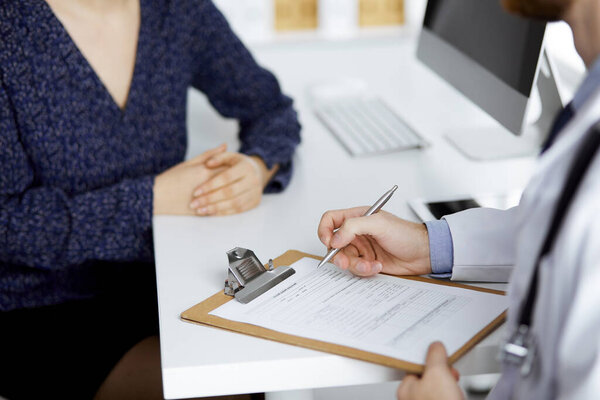 Женщина-врач и мужчина обсуждают текущее обследование здоровья, сидя в клинике крупным планом. Концепция медицины