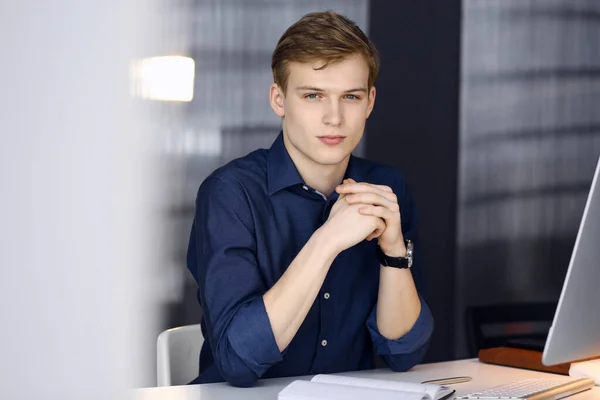 Young blond businessman thinking about strategy at his working place with computer. Startup business means working hard and out of time for success achievement