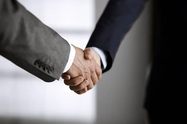 Business people in office suits standing and shaking hands, close-up. Business communication concept. Handshake and marketing