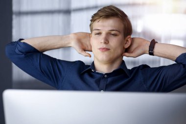 Genç sarışın işadamı ve programcı karanlık bir ofiste bilgisayarla sıkı çalıştıktan sonra el ele tutuşuyor, arka planda ışık parlıyor.