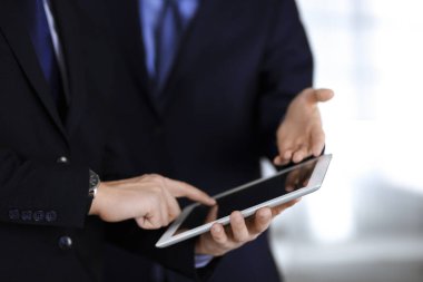 İş adamları yeni projelerini tartışmak için bir tablet bilgisayar kullanıyorlar, modern bir ofiste duruyorlar. İş yerinde iş arkadaşı olan tanınmamış bir iş adamı ya da erkek girişimci. Takım çalışması ve ortaklık