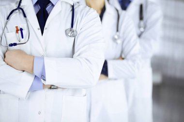 Hastane ofisinde çapraz kolları ve steteskopları olan bir grup modern doktor bir takım gibi duruyor. Doktorlar hastaları muayene etmeye ve yardım etmeye hazır. Tıbbi yardım, sağlık sigortası, en iyi hastalık