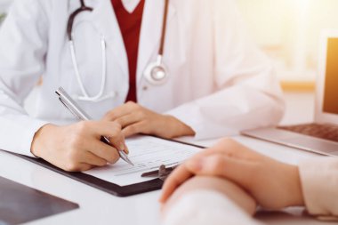 Bilinmeyen kadın-doktor hastaya danışmanlık yaparken başvuru formu dolduruyor. güneşli oda tıp konseptinde