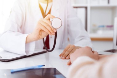 Sunny Room 'da elinde steteskop olan tanınmamış bir kadın doktor, yakın plan. Tıp konsepti