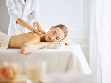 Güzel bir kadın kapalı gözlerle sırt masajından hoşlanıyor. Spa tedavisi kavramı