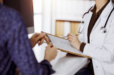 Doktor ve hasta güneşli klinikte otururken sağlık muayenesini tartışıyorlar. Hastanede mükemmel bir tıbbi hizmet.