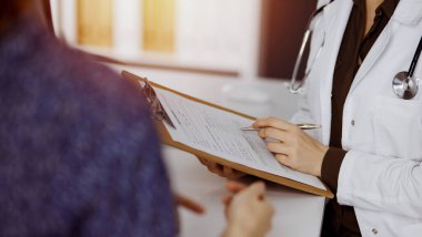 Doktor ve hasta güneşli klinikte otururken sağlık muayenesini tartışıyorlar. Hastanede mükemmel bir tıbbi hizmet.