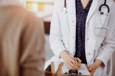 Doktor ve hasta güneşli klinikte otururken sağlık muayenesini tartışıyorlar. Hastanede mükemmel bir tıbbi hizmet.