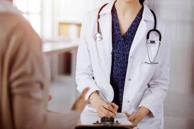 Doktor ve hasta güneşli klinikte otururken sağlık muayenesini tartışıyorlar. Hastanede mükemmel bir tıbbi hizmet.