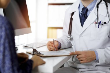 Dost canlısı kızıl sakallı doktor ve hasta kadın güneşli klinikte otururken sağlık muayenesini tartışıyorlar. Tıp konsepti