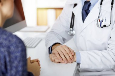 Kadın doktor ve erkek hasta güneşli klinikte otururken sağlık muayenesini tartışıyorlar. Yakın plan. Tıp konsepti