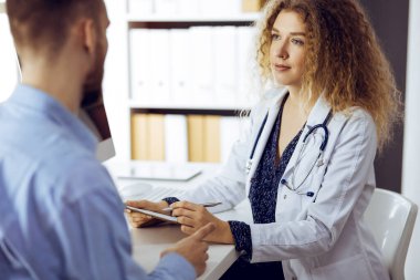 Kadın doktor ve erkek hasta güneşli klinikte otururken sağlık muayenesini tartışıyorlar. Tıp konsepti