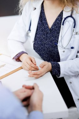 Kadın doktor ve erkek hasta güneşli klinikte otururken sağlık muayenesini tartışıyorlar. Yakın plan. Tıp konsepti