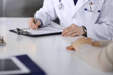 Bilinmeyen erkek doktor ve hasta kadın klinikte oturup dosya kullanırken bir şey tartışıyorlar. Hastanedeki en iyi sağlık hizmeti, ilaç, salgın durdurma.