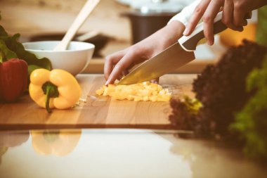 Mutfakta pişen bilinmeyen insan elleri. Sarı dolma biber dilimleyen kadın. Sağlıklı yemek ve vejetaryen gıda konsepti.