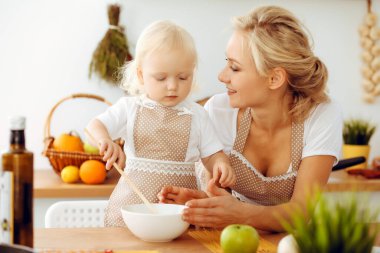 Mutfakta yemek pişiren mutlu anne ve küçük kız. Birlikte vakit geçirmek, aile eğlencesi konsepti.