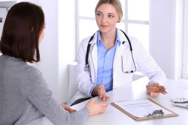 Hastane muayenehanesindeki genç kadın doktor ve hasta. Terapistin mavi renkli bluzu iyi görünüyor. Tıp ve sağlık hizmetleri kavramı