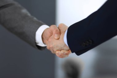 İş adamları toplantıdan ya da pazarlıktan sonra iş arkadaşlarıyla el sıkışıyorlar. Yakın plan. Modern ofisteki bir grup tanınmamış iş adamı ve kadın. Takım çalışması, ortaklık ve tokalaşma