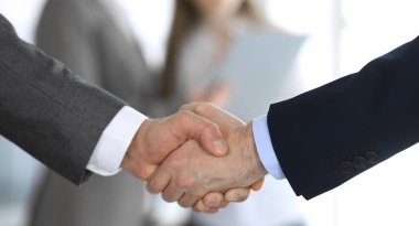 İş adamları toplantıdan ya da pazarlıktan sonra iş arkadaşlarıyla el sıkışıyorlar. Yakın plan. Modern ofisteki bir grup tanınmamış iş adamı ve kadın. Takım çalışması, ortaklık ve tokalaşma