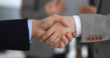 İş adamları toplantıdan ya da pazarlıktan sonra iş arkadaşlarıyla el sıkışıyorlar. Yakın plan. Modern ofisteki bir grup tanınmamış iş adamı ve kadın. Takım çalışması, ortaklık ve tokalaşma