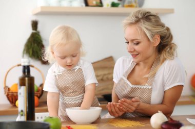 Mutfakta yemek pişiren mutlu anne ve küçük kız. Birlikte vakit geçirmek, aile eğlencesi konsepti.